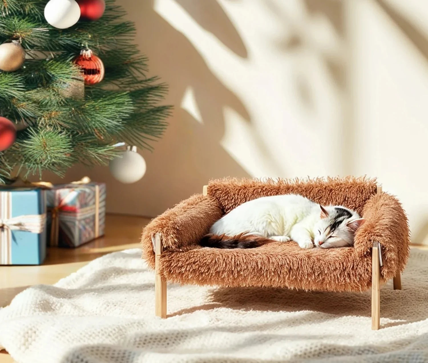 White cat napping on the plush cat couch next to a Christmas tree